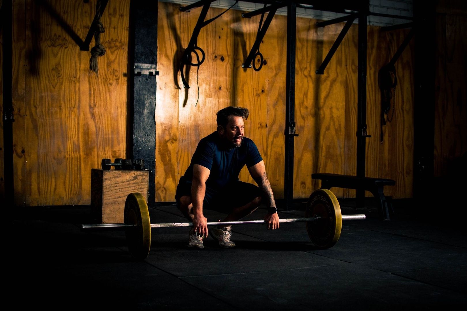 Man förbereder ett tungt marklyft i ett mörkt gym
