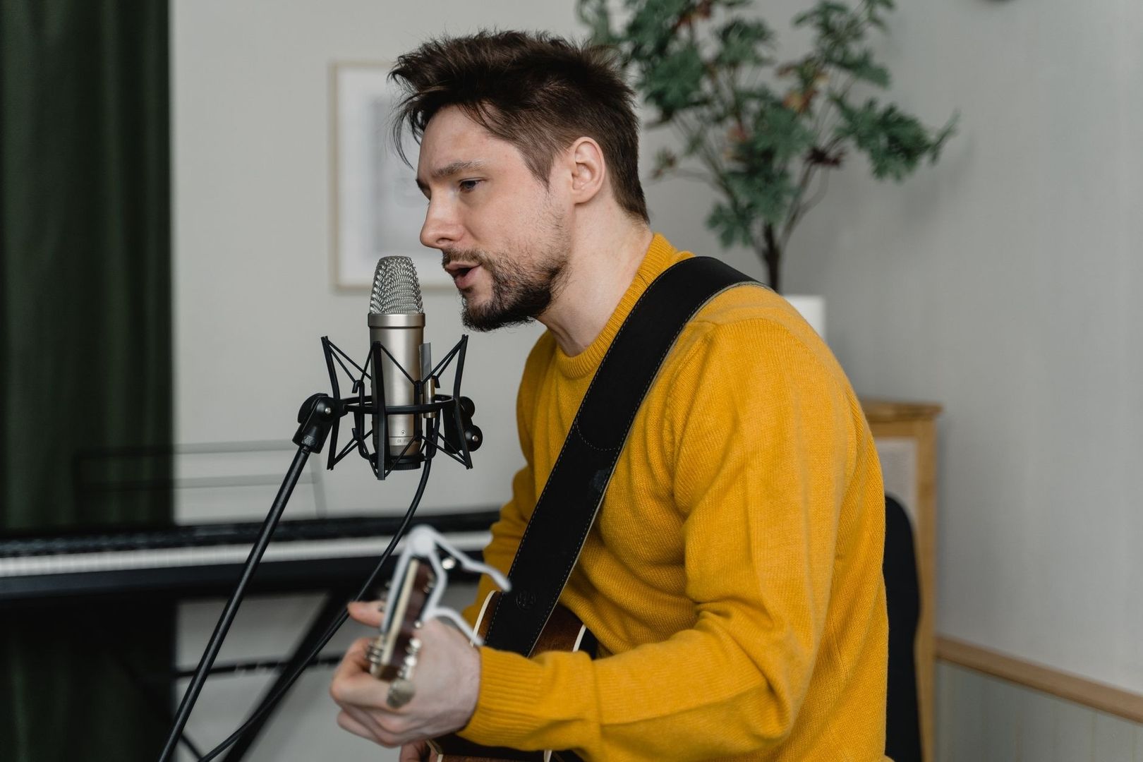 Sångare spelar gitarr nära en studiomikrofon i hemmiljö